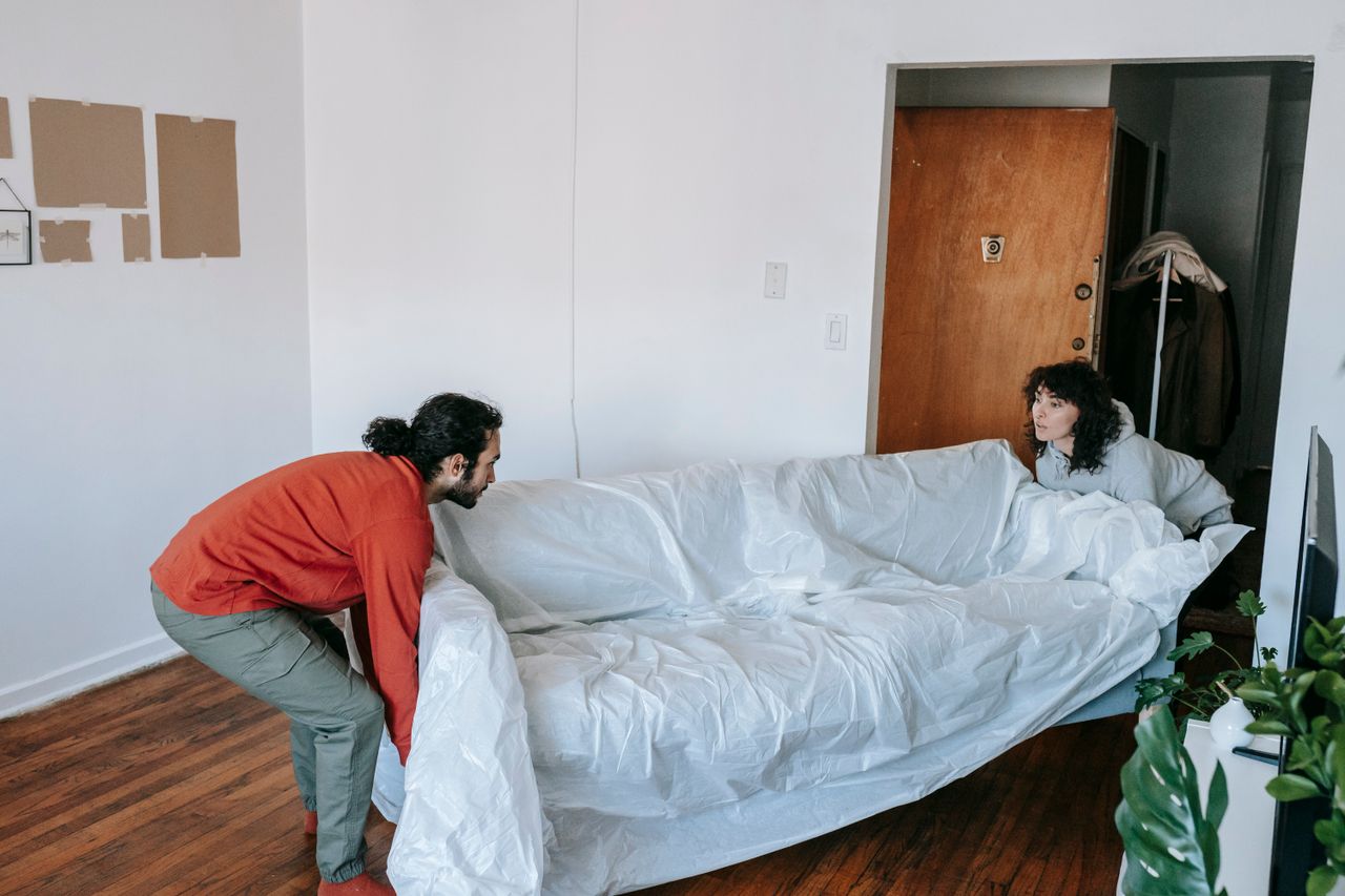 gallery-04 A couple collaboratively lifting a couch while moving into a new apartment.