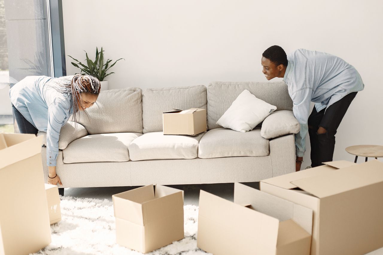 home-img Happy couple setting up a sofa in their new home surrounded by moving boxes.